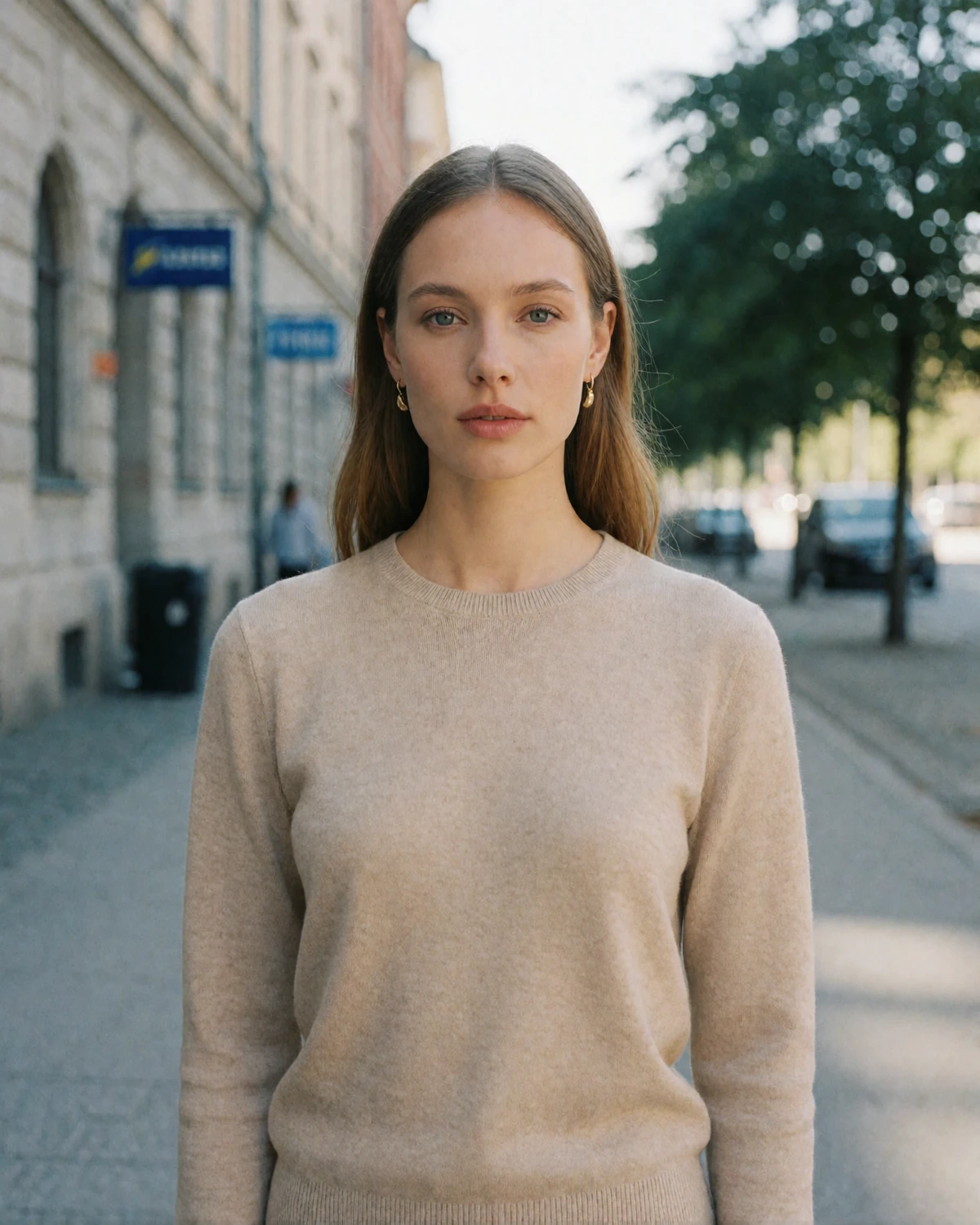 Swedish woman in her early thirties with fair hair standing on a bright Nordic city street looking directly at the camera